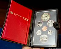 Photo showing the open black box with red satin interior and the set of 7 silver proof coins displayed in a protective case.