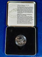 Sterling silver coin in protective case with descriptive card in English and French detailing the design and commemoration.
