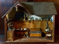 Front view of the miniature pub diorama showcasing interior furnishings with wooden bench, tables, miniature bottles and pewter cups, and hanging chandelier.