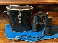 Carl Metzlar binoculars with original leather carrying case set on blue cloth.