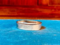 Thick wide sterling silver bangle laid flat, clasp visible