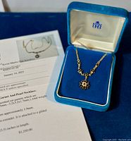 Full view of garnet and pearl necklace in Birks box alongside appraisal document