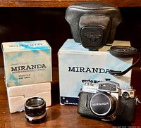 Photo of the camera with the additional 5cm lens in original box, original camera box, leather case, and strap.
