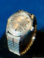 Front three-quarter view showing dial, applied markers, date window, and expansion band