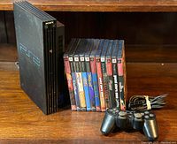 Full lot shot showing console upright, game cases stacked, controller and cables front