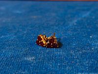 Close-up of the pair of vintage sterling silver stud earrings with triangular garnet cluster set against blue fabric.