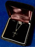 Crucifix necklace displayed inside a jewelry box with velvet and satin lining, showing overall item condition and packaging.