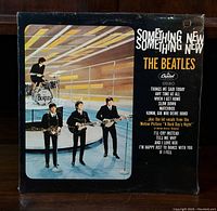 Front cover of 'Something New' by The Beatles vinyl album showing band members on stage and song list.