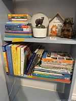 Shelf with stacked children's books including Mercer Mayer works and some thin paperbacks on the right.