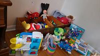 Overview of children's toys including Fisher-Price garage playset, plush toys, toy cars, and The Fishing Game box