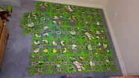 Fully assembled 27-piece foam puzzle play mat with city and road theme placed on floor, showing roads, buildings, and various urban details.