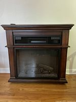Frontal view of the electric fireplace showing the wooden frame and black vent panel.