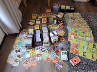 Overview of the entire lot showing multiple stacks of sleeved cards, loose cards spread out, and accessory pieces.