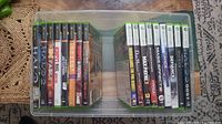 Photo showing the full lot of 17 Xbox Original and Xbox 360 games neatly arranged in a storage container for display and review.