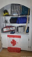 Shelved camping gear including backpack, lounger, camping tent, sleeping bags, shoes, camping stove, and Canadian flag displayed