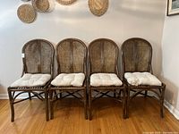 Front view of all four rattan chairs showing woven backrests and seat bases with removable cushions.