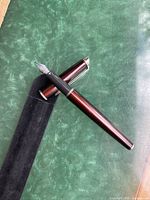 Waterman burgundy fountain pen with silver nib and metal trims placed on green velvet surface.