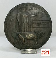 Front view of the bronze commemorative medallion showing the full relief design with the female figure, lion, and inscription honoring Donald Victor Scotton.