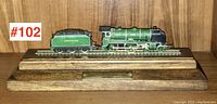 Side view of green Southern model train and coal tender on wooden base with plaque.