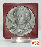 Front view of the commemorative medallion with detailed relief portrait of Alexander Pushkin on a red frame.