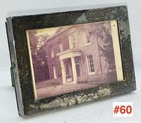 Front angle view showing the tarnished sterling silver frame holding the sepia-toned photo of a stately brick house.