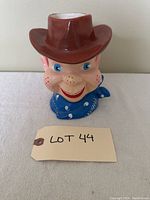 Front view of 1950s Howdy Doody ceramic head vase showing brown cowboy hat, blue bandana, smiling face with blue eyes and red freckles