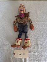 Front view of the full Howdy Doody marionette puppet laid flat showing clothing and boots with 'HD' logo.