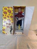 Full shot of Howdy Doody doll in original box showing packaging, doll, and how it is secured inside the box with accessories and manual beside.