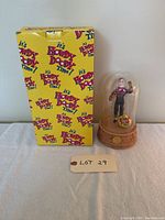 Front view of the boxed collectible Howdy Doody musical figurine with glass dome on right.