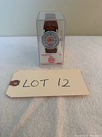 Front view of Howdy Doody wristwatch in clear plastic box showing character dial and brown strap.