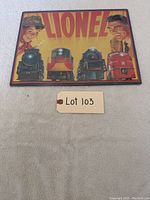 Front view of the Lionel tin sign with four train images and two men, showing original plastic wrapping and excellent condition.