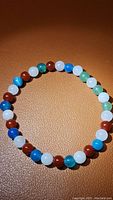 Photo showing the natural gemstone bracelet arranged on a textured brown background, highlighting the vibrant color of carnelian, agate, jade, and aventurine beads