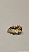 Clear image of pear cut natural golden citrine gemstone on plain background, showing faceted details and color.