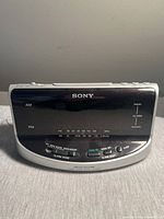 Front view of a vintage Sony Dream Machine AM/FM clock radio with digital tuning scale and several buttons on top for alarm mode and reset.