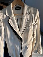 White Ann Demulemeester jacket on hanger, close-up showing fabric and lapels