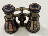 Front oblique view of opera glasses showing brass frame and mother-of-pearl panels
