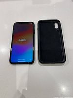 iPhone XR powered on showing setup screen beside black protective case