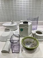 Disassembled juicer parts including pulp filter, feed chute, pusher, juice container and motor base with control dial