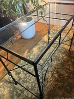 Close-up of the glass top and black metal frame showing the structure and support details of the console table.