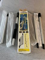 Multiple metal extension rods and black plastic grip parts laid out with original Karcher packaging showing product details and usage images.