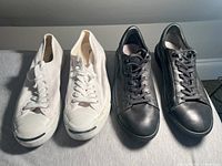 Front view of both pairs of sneakers together, showing white Converse on the left and black Diesel leather on the right.
