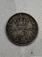Close-up photo of the 1911 British 3 Pence coin showing crown above the numeral 3 and the date split '19' and '11'