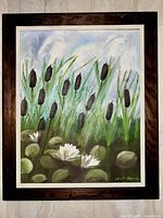 Framed oil or acrylic painting by artist M. Nordstrands showing cattails and white water lilies in a pond scene, good condition.