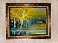 Framed original oil painting by Edgar Victor Brastins showing a landscape with golden birch tree and cabin near water.