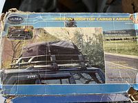 Box with wear showing product image of Ultra Radian rooftop cargo carrier mounted on a Jeep roof rack.