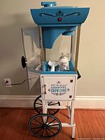 Full view of snow cone machine on cart against wall with power cord