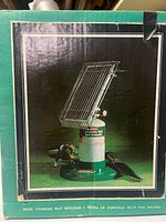 Box with image of vintage Coleman propane heater connected to a propane canister (not included), showing green and chrome components.