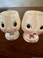 Front view of the His and Hers ceramic egg cups showing facial features and bow ties.
