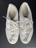 Top view of left and right vintage Nike running shoe, showing white mesh and leather uppers, white laces, and gum soles.