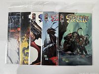 Five Spawn comic books in protective sleeves, arranged side by side showing partial covers and issue numbers 65-69.